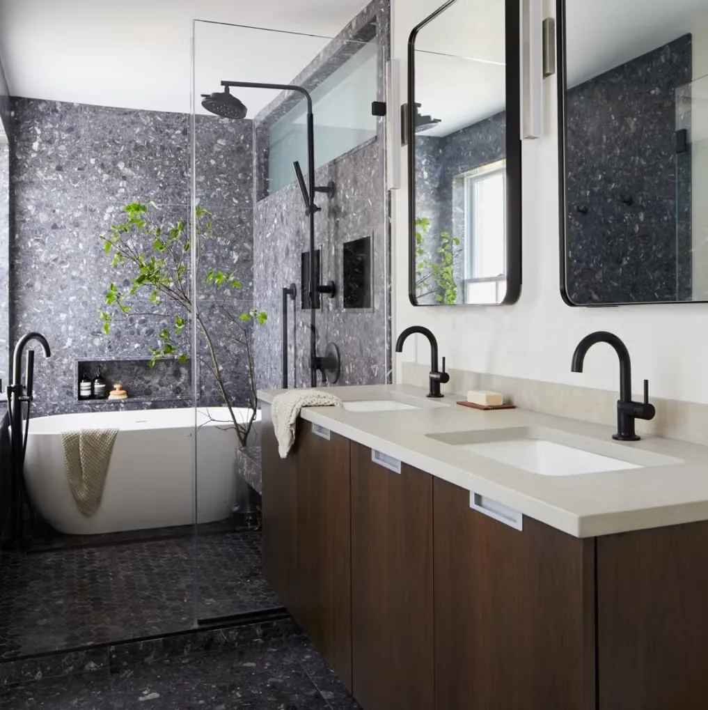 Modern bathroom with stone tile, shower, and double vanity.