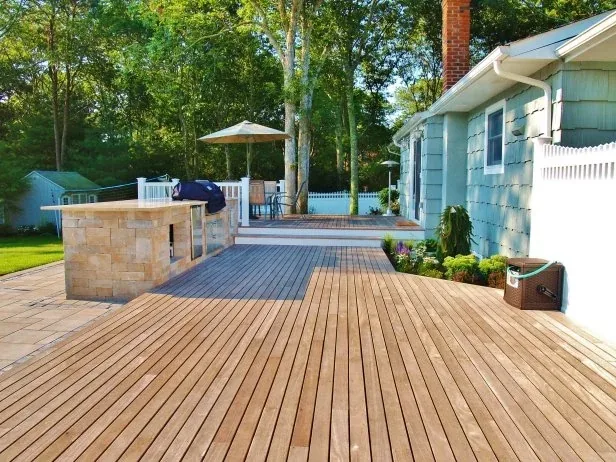 Spacious multi-level wooden deck with stone outdoor kitchen.